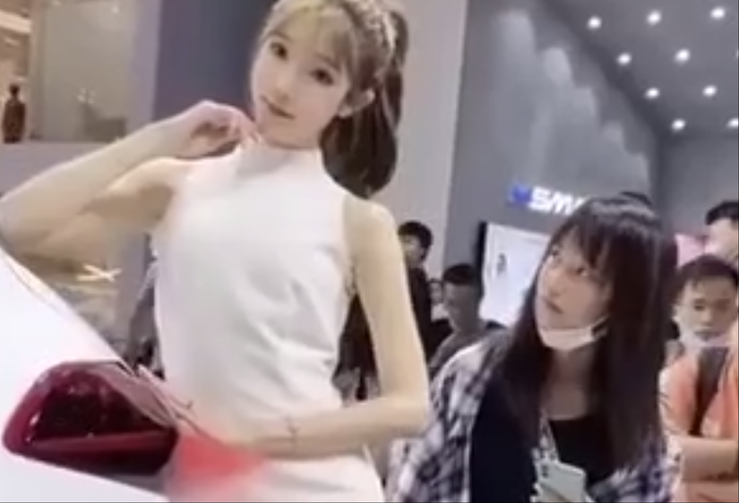 На выставке машин азиатская девушка с недоверием ощупывала модель, думая, что это пластиковый манекен